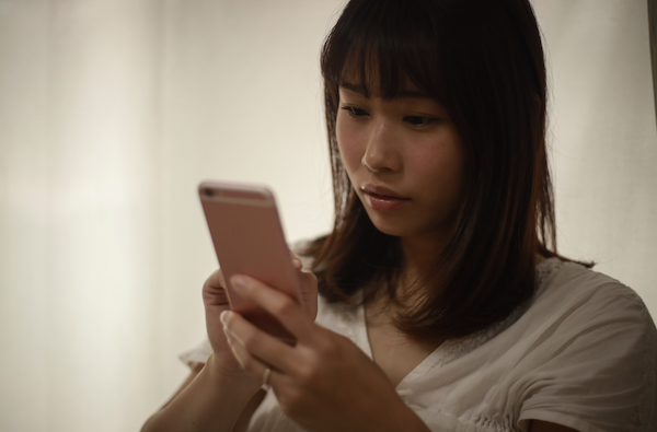 彼から突然LINEがブロックされて連絡が途絶え、ショックを受けてアプリを呆然と見つめるアラフォー婚活女性